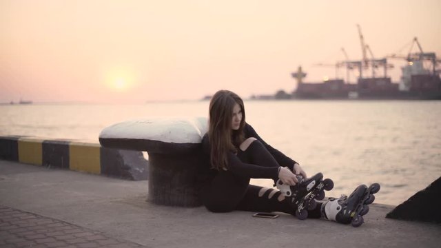 Woman skating by the sea. The girl goes rollerblading and does tricks. Caucasian woman outdoor at sunrise