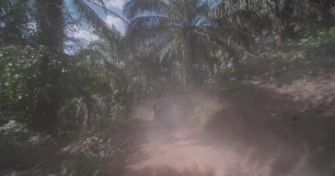 Driving behind quad bike, ATV drivers through tropical jungle foresrt during sunny summer day