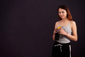 sports girl after playing sports drinks from a shaker with a wet shirt from sweat on a dark background copyspace