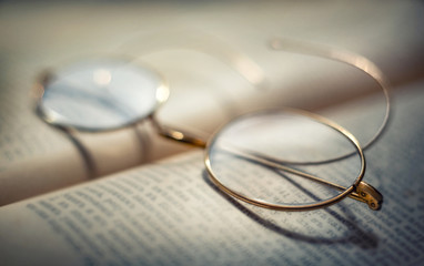 Vintage Eyeglasses and antique old book. Retro style. Concept idea on the topic of science, education, history, etc. Shallow depth of field, selective focus.