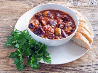 a bowl of braised veal with olives, eggplant, and tomatoes stewed in red  wine