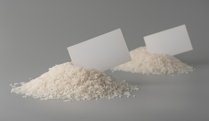 Pile of uncooked rice grains with blank label on grey background