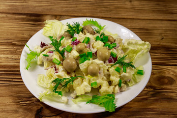 Potato salad with marinated mushrooms, eggs, red onion and mayonnaise on wooden table