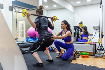 Fototapeta na wymiar Athletic woman during functional workout with electric muscle stimulation in fitness gym. EMS electro stimulation women exercises with trainer coach