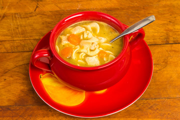 Chicken Noodle Soup in Bright Red Bowl on Rustic Wood Table