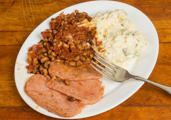 Soul Food Plate of Fried Spam with Hoppin' John Peas and Potato Salad on Rustic Wood Table
