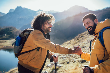 Helping hand - hiker man getting help on hike happy overcoming obstacle.