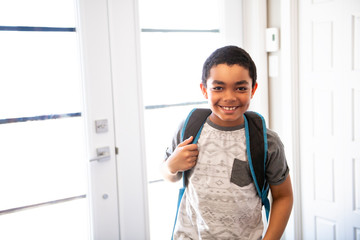 A child boy coming home passing through the door after school