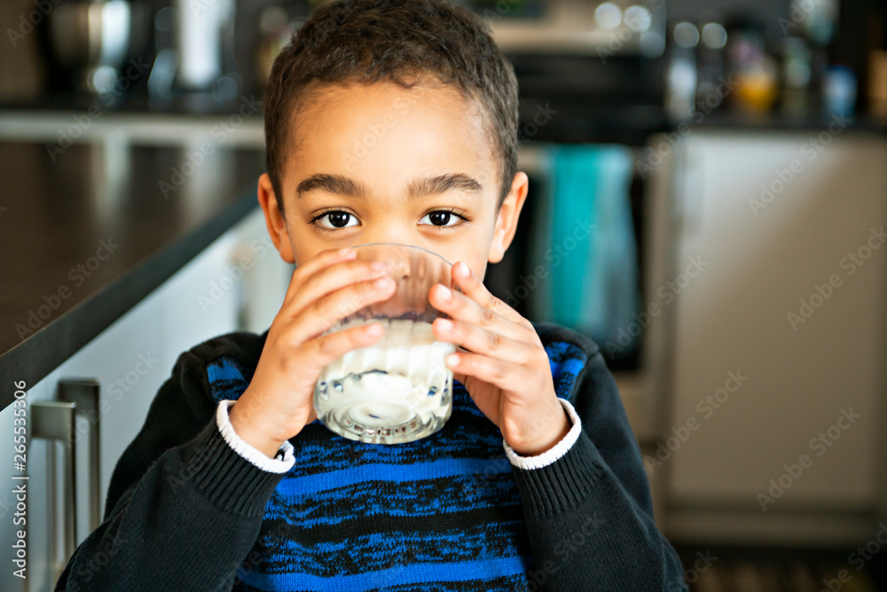 Wall mural Cute African American boy drinking milk at home