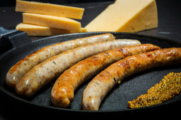 macro frying pan with fried thin sausages and granular mustard