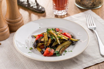 Grilled vegetables warm salad with eggplant and tomato with tomato juice on wooden table