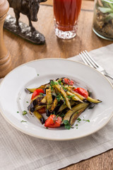Grilled vegetables warm salad with eggplant and tomato with tomato juice on wooden table