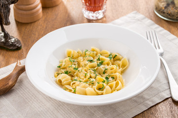 Conchiglie pasta with herbs and glass of tomato juice on wooden table