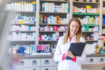 Smiling female pharmacist working in chemist shop or pharmacy. Female happy pharmacist chemist woman standing in pharmacy drugstore