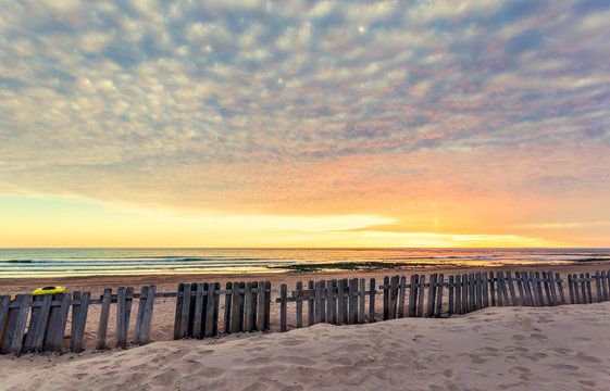 Fence on sand beach at sunset in Chipiona