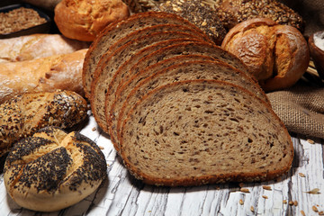 Assortment of baked bread and bread rolls on rustic white bakery table background