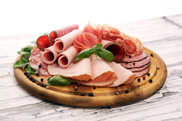 Food tray with delicious salami, pieces of sliced ham, sausages,salad and vegetable. Meat platter with selection