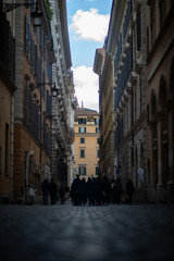 Fototapeta na wymiar Narrow dark street with people in the center of Rome