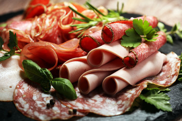 Food tray with delicious salami, pieces of sliced ham, sausages,salad and vegetable. Meat platter with selection