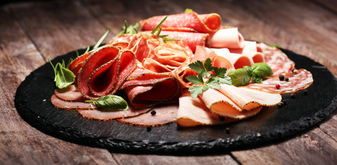Food tray with delicious salami, pieces of sliced ham, sausages,salad and vegetable. Meat platter...