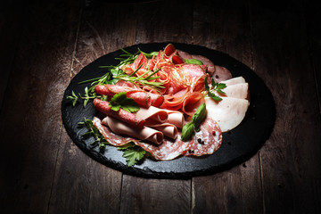 Food tray with delicious salami, pieces of sliced ham, sausages,salad and vegetable. Meat platter with selection