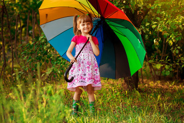 Happy child girl walk with multicolored umbrella under rain