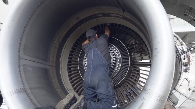 Engineer, technician examines the jet engine with a flashlight. The repair of aircraft in the hangar. Maintenance of aircraft. 4k