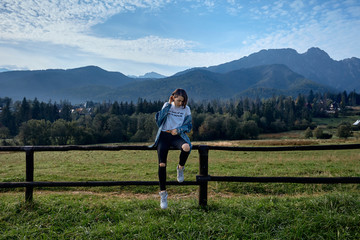 Girl sitting on grass. Mountains as a background