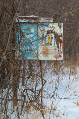 A rusty vintage old phone box (I think) on a pole that no longer had a phone in it - next to remote area railroad tracks - cold snowy wintery day