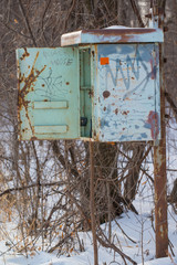 A rusty vintage old phone box (I think) on a pole that no longer had a phone in it - next to remote area railroad tracks - cold snowy wintery day