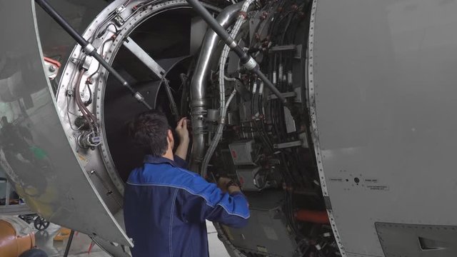 Engineer, technician examines the jet engine with a flashlight. The repair of aircraft in the hangar. Maintenance of aircraft. 4k