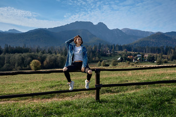 Obraz premium Girl sitting on grass. Mountains as a background