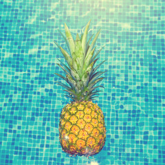 Pineapple swimming in water, poolside.
