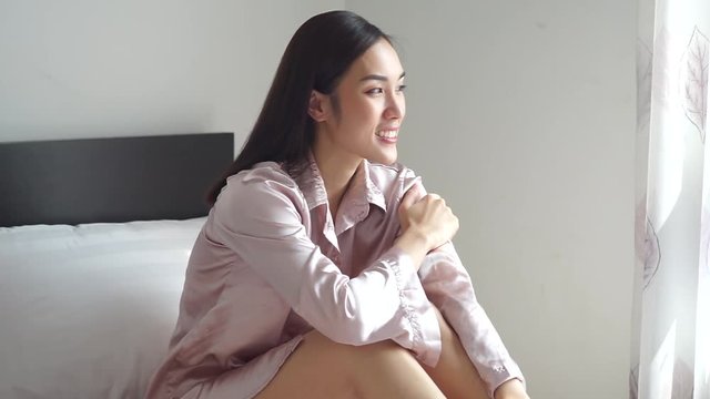 Asian woman sitting on her bed and smile