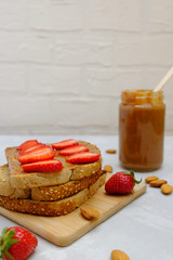 Almond butter and strawberry toasts on neutral background, selective focus.