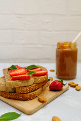 Almond butter bread with strawberry slices on neutral background, selective focus