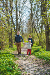 Obraz premium family of three walking by park trail in sunny day