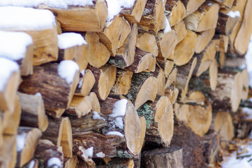 Snowy wood pile with cut wood for fires and heat