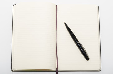 Open black leather notebook with pen isolated on a white background. Moleskin 