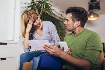 Photo of a young couple embracing and calculating the bills at home.