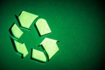 Close up of recycling symbol in raised texture on smooth green background