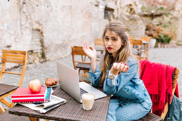 Fair-haired pretty girl worried and surprised, can't connect to public wi-fi at the outdoor cafe....