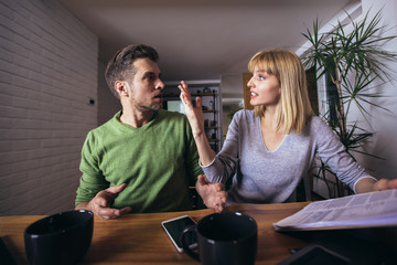 Couple sitting at the desk at home read notice paper check bills or bank account balance