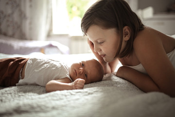 older sister kisses baby for 1 month, embraces