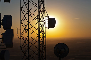 Silhouette of communications tower against sunset sky