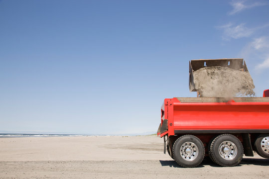 Truck shoveling sand on beach