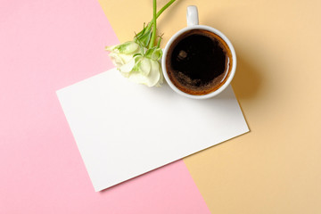 Blank paper card with copy space, cup of coffee and white roses flowers on colorful background. Concept of love, tenderness, morning breakfast, dating, freshness. Women desk. Creative minimal design.