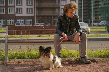 sad lonely guy sitting on a bench with his dog. the difficulties of adolescence in communication...