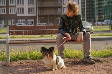 sad lonely guy sitting on a bench with his dog. the difficulties of adolescence in communication...