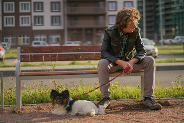sad lonely guy sitting on a bench with his dog. the difficulties of adolescence in communication...